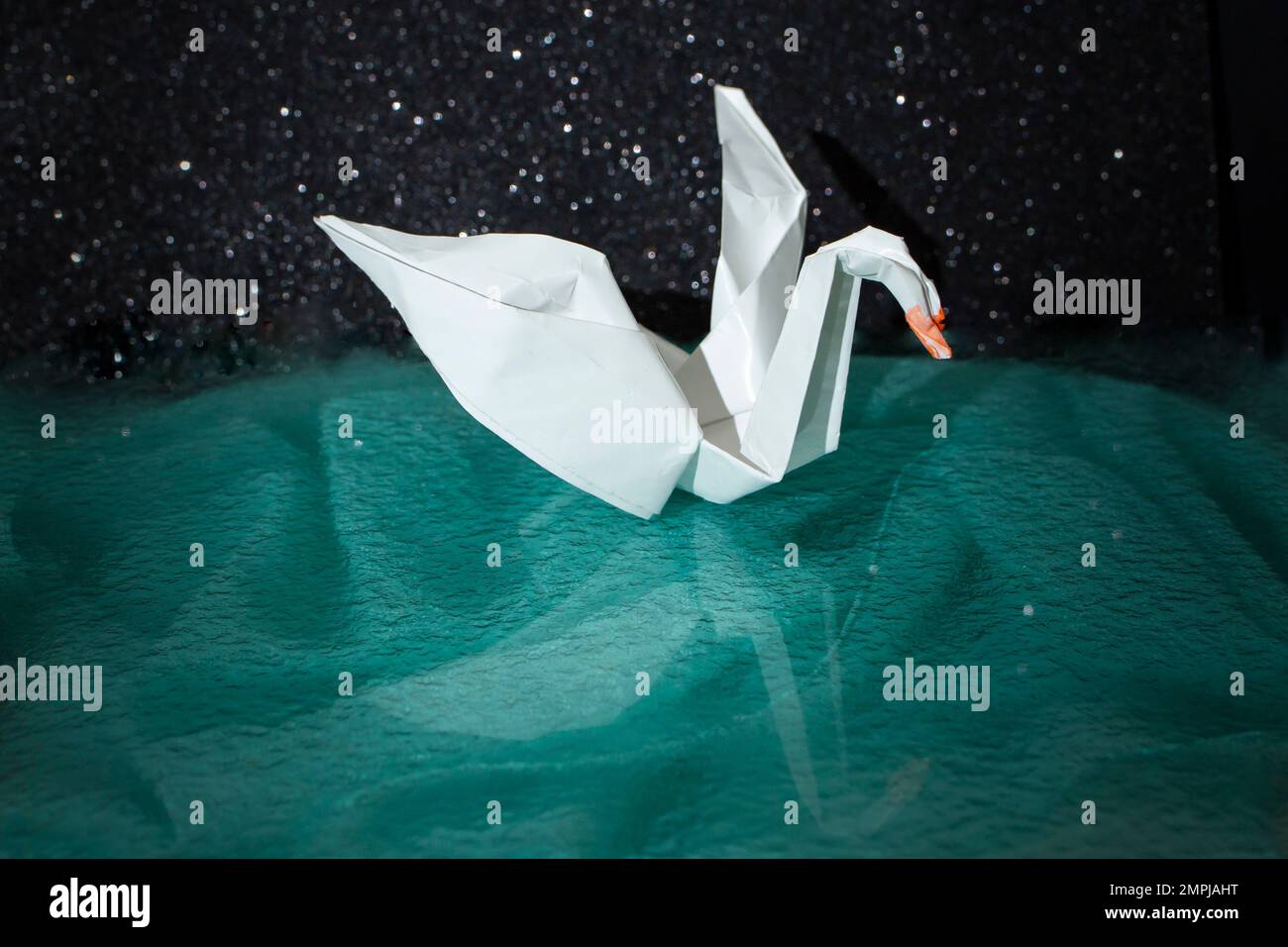 Papier blanc origami cygne sur fond vert foncé, flou de gros plan Banque D'Images