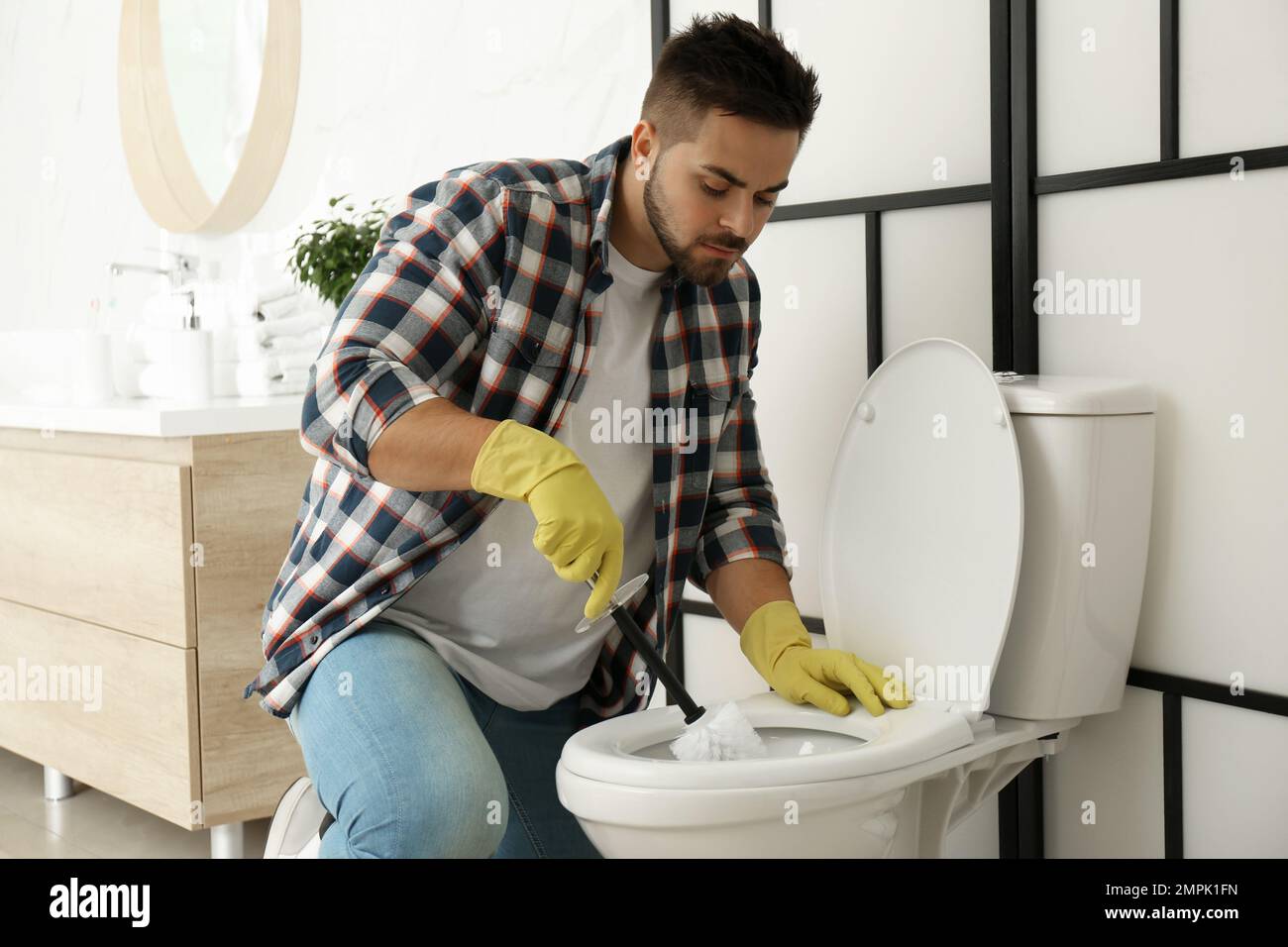 Jeune homme nettoyant cuvette de toilettes dans la salle de bains Photo  Stock - Alamy