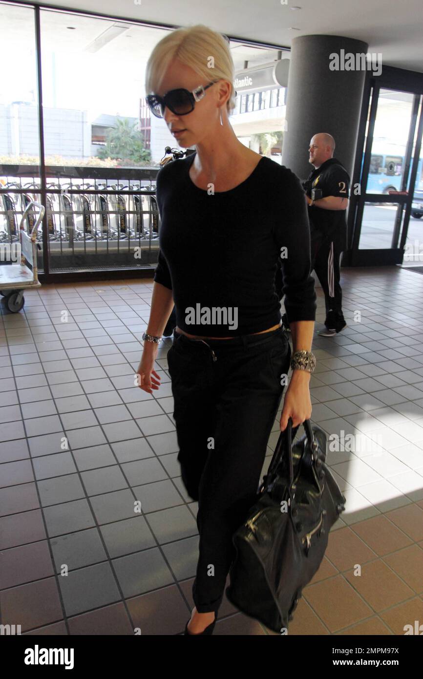 Charlize Theron porte un pantalon noir, des talons noirs et un petit haut  noir qui revelas sa taille de garniture lorsqu'elle arrive à LAX. Charlize  se dirige à l'étranger pour filmer son