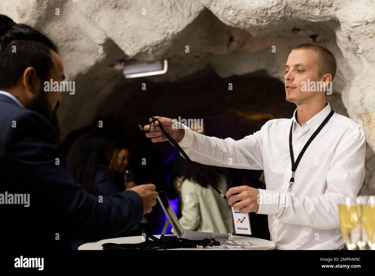 Jeune réceptionniste qui donne une carte d'identité à l'homme d'affaires pendant la conférence au centre de congrès Banque D'Images