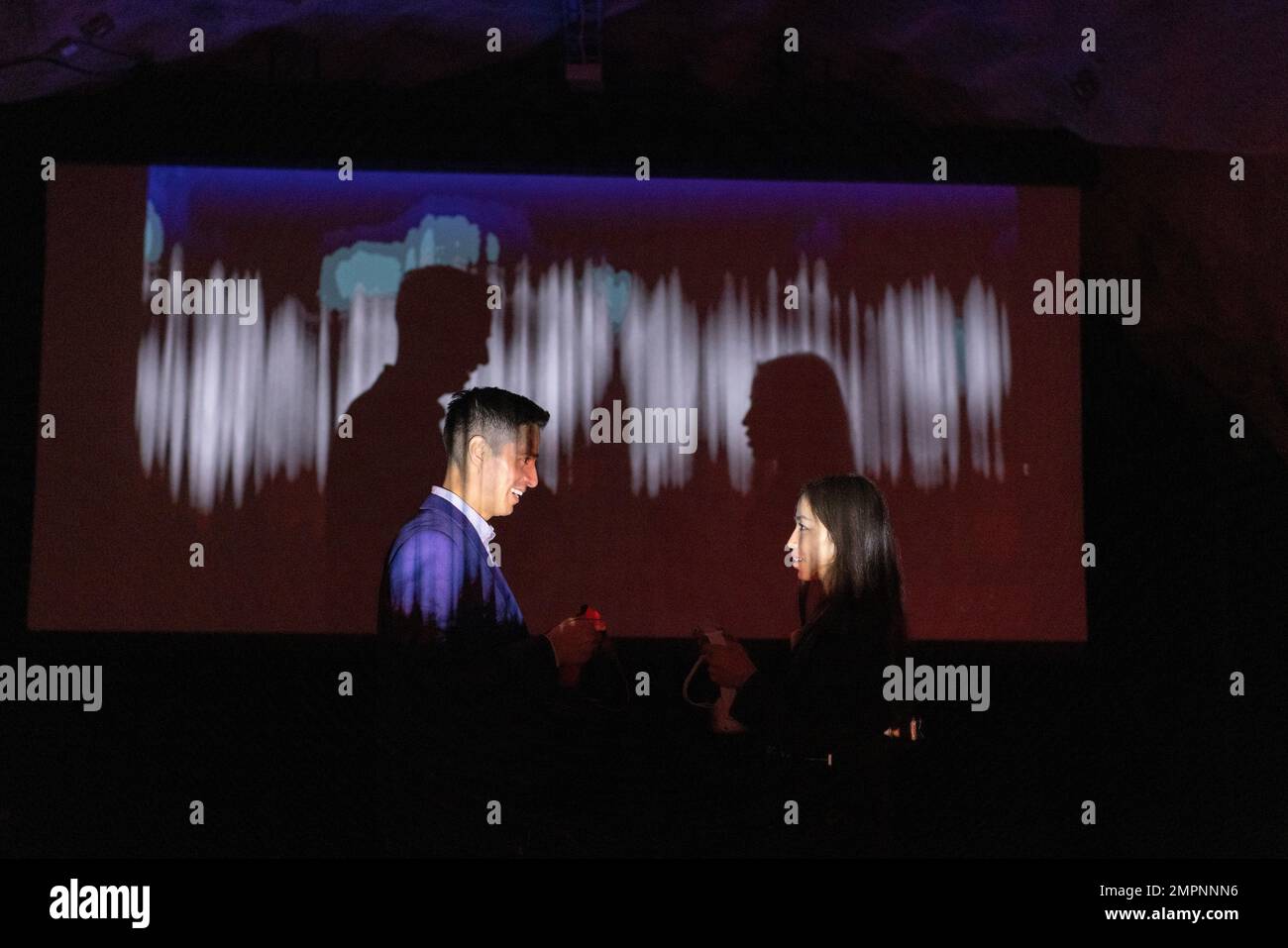 Vue latérale des collègues de travail discutant par écran de projection dans l'atelier éclairé Banque D'Images