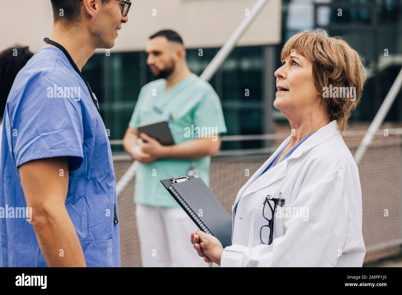 Vue latérale d'un collègue de sexe masculin discutant avec un médecin de sexe féminin Banque D'Images