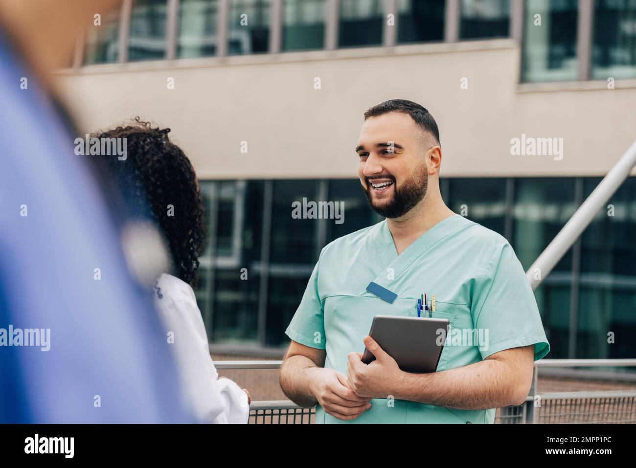 Un professionnel de la santé qui tient un PC tablette et qui parle à une collègue féminine Banque D'Images