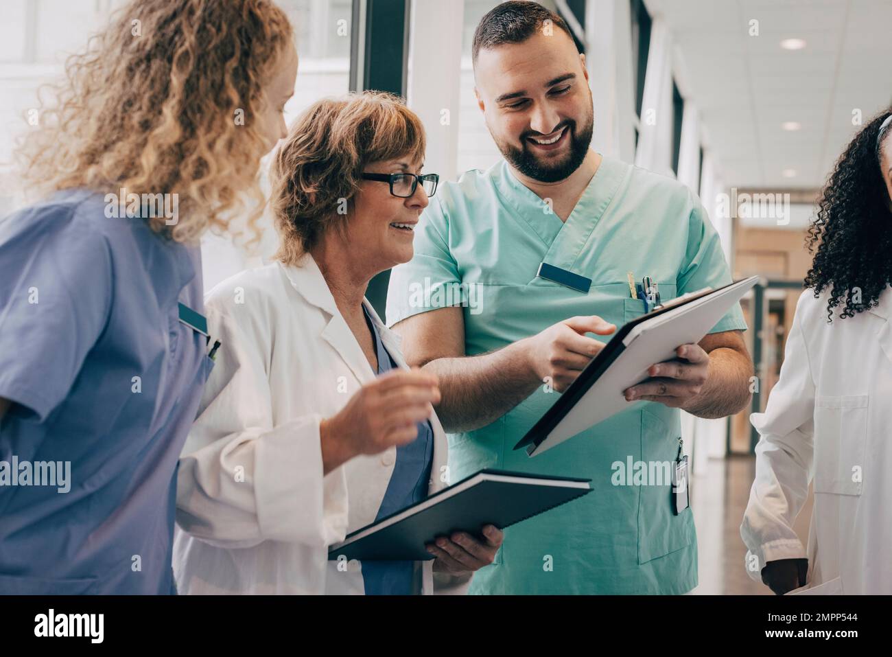 Une équipe médicale multiraciale souriante discutant sur presse-papiers à l'hôpital Banque D'Images
