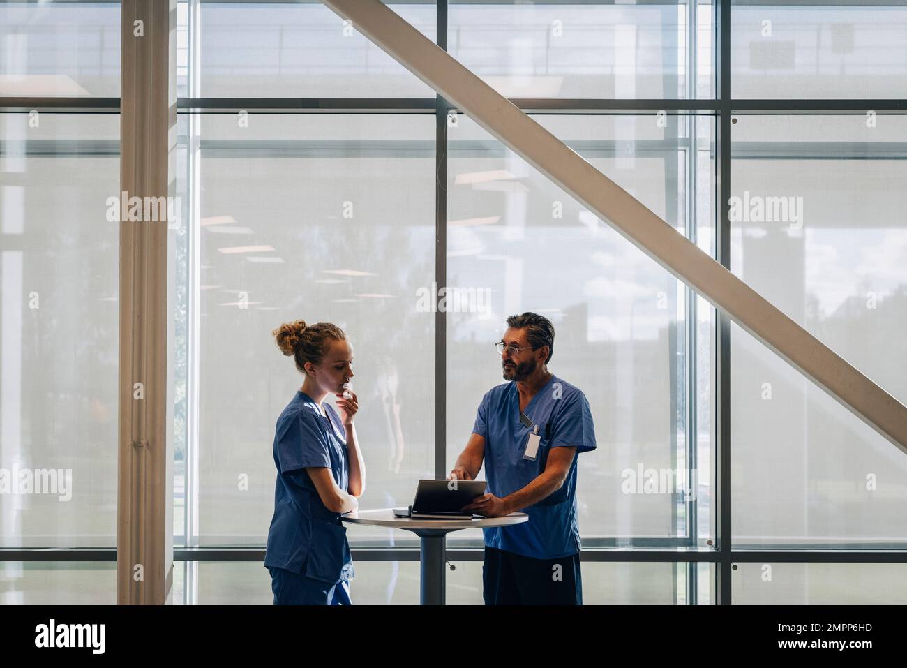 Un médecin de sexe masculin explique la collègue féminine au sujet d'un PC tablette à l'hôpital Banque D'Images
