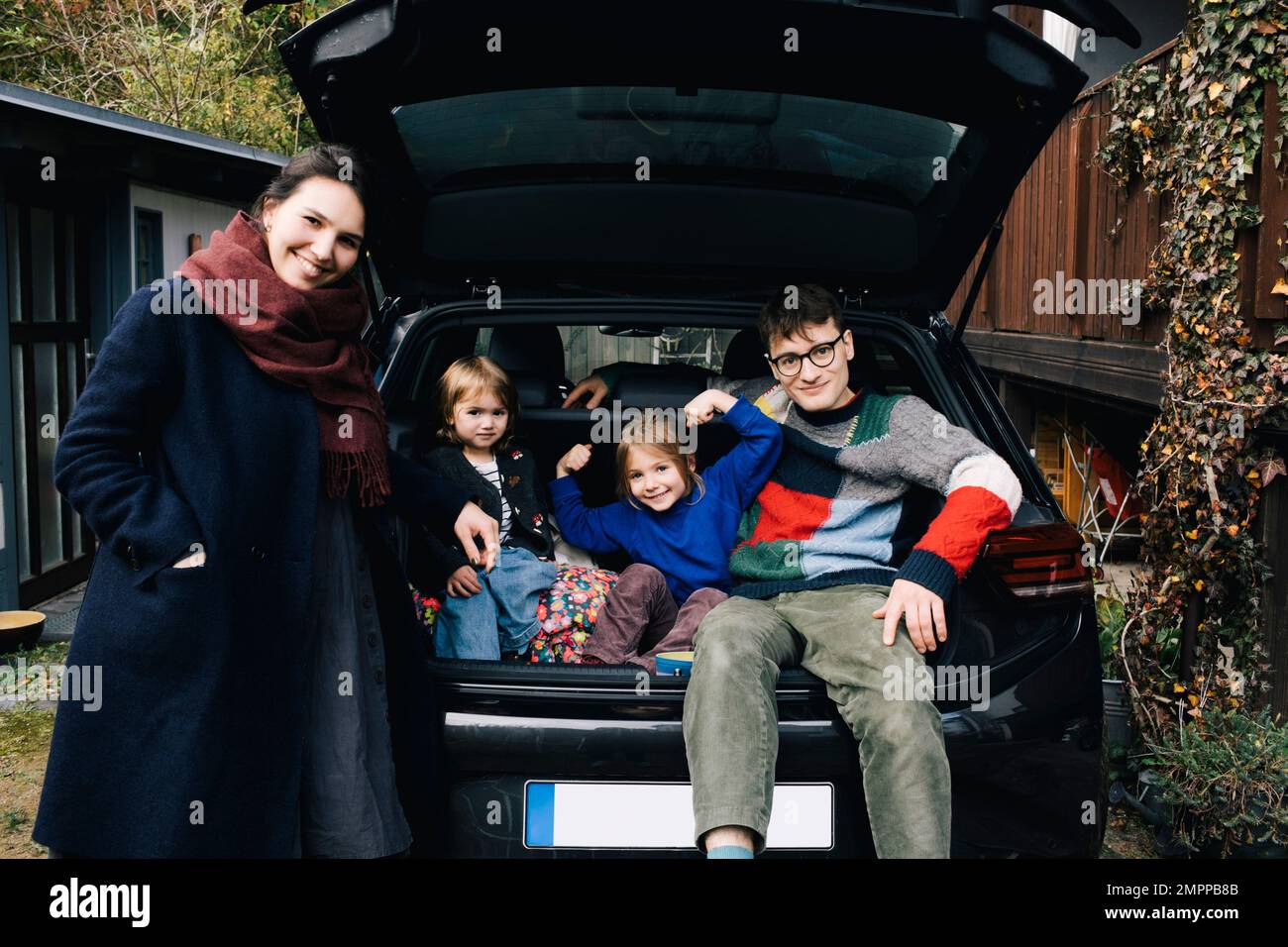 Famille heureuse avec voiture électrique appréciant ensemble dans la cour arrière Banque D'Images