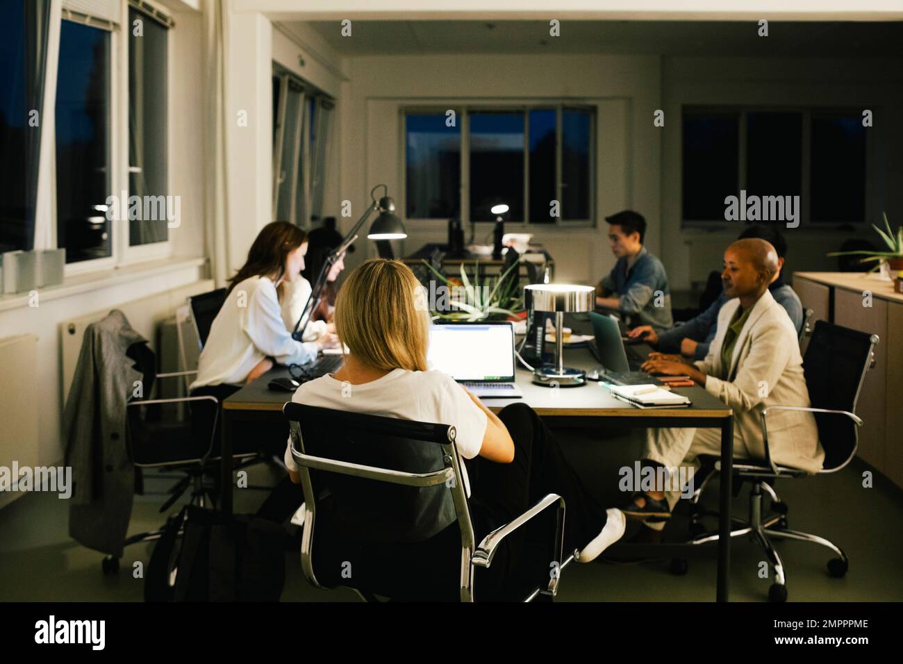 Les collègues travaillent tard lorsqu'ils sont assis à leur bureau Banque D'Images