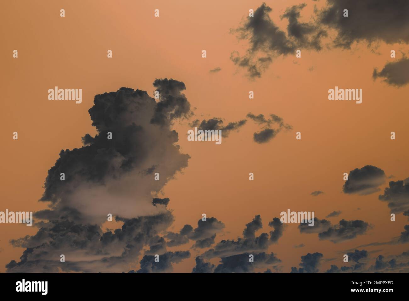 Une photographie abstraite de cumulus nuages contre un ciel orange vif. Banque D'Images