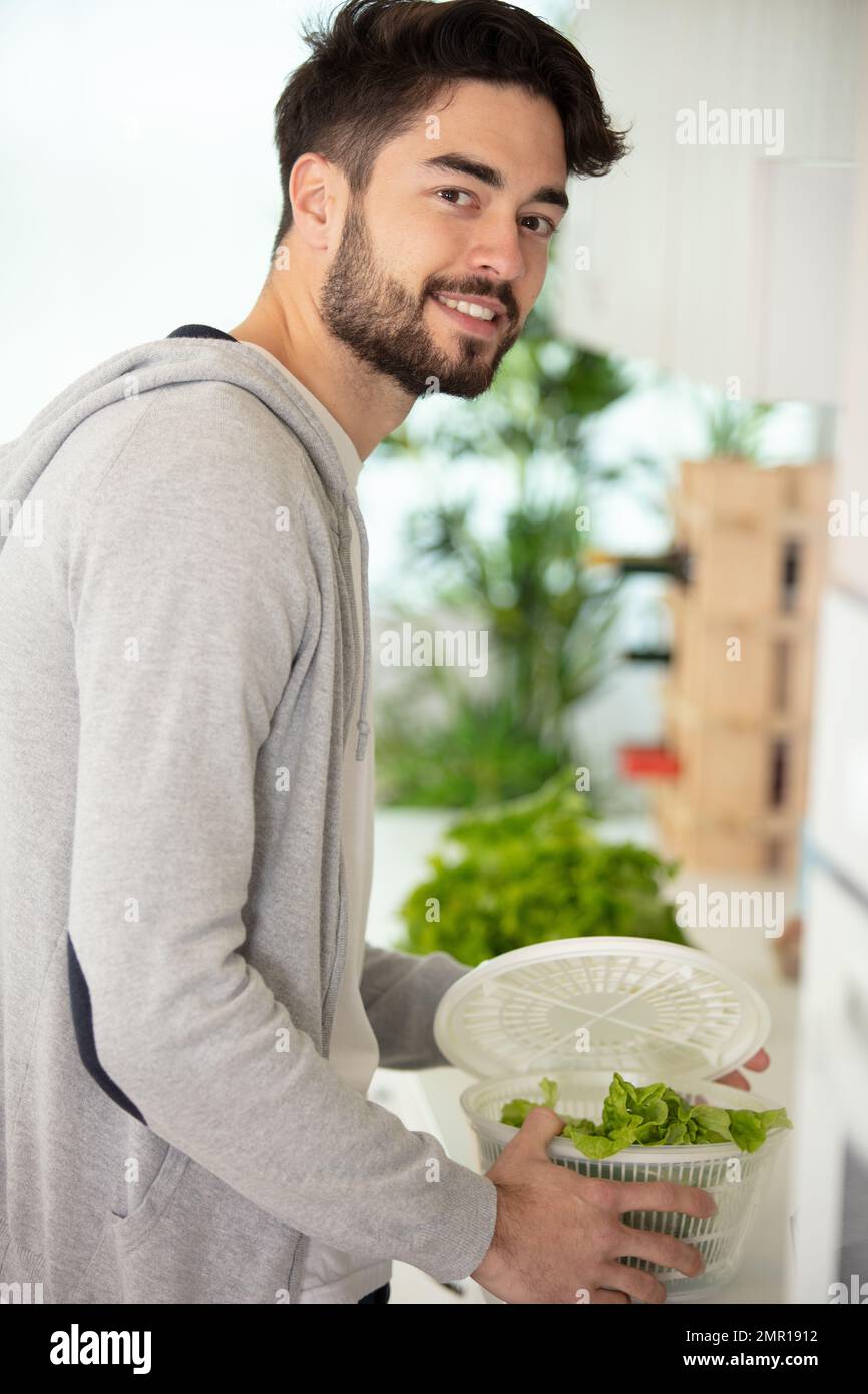 homme séchant de la laitue dans une tournette en plastique Banque D'Images