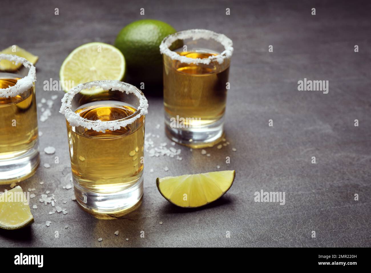 Prises de Tequila mexicaines, tranches de lime et sel sur table grise Banque D'Images