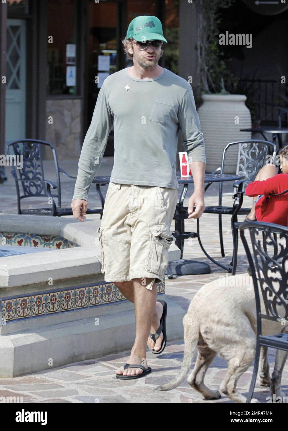 Gerard Butler dans un chapeau de baseball vert, t-shirt et short est vu se  diriger vers une pizza locale pour un morceau à manger. Se mêlant comme un  local de Malibu, Butler