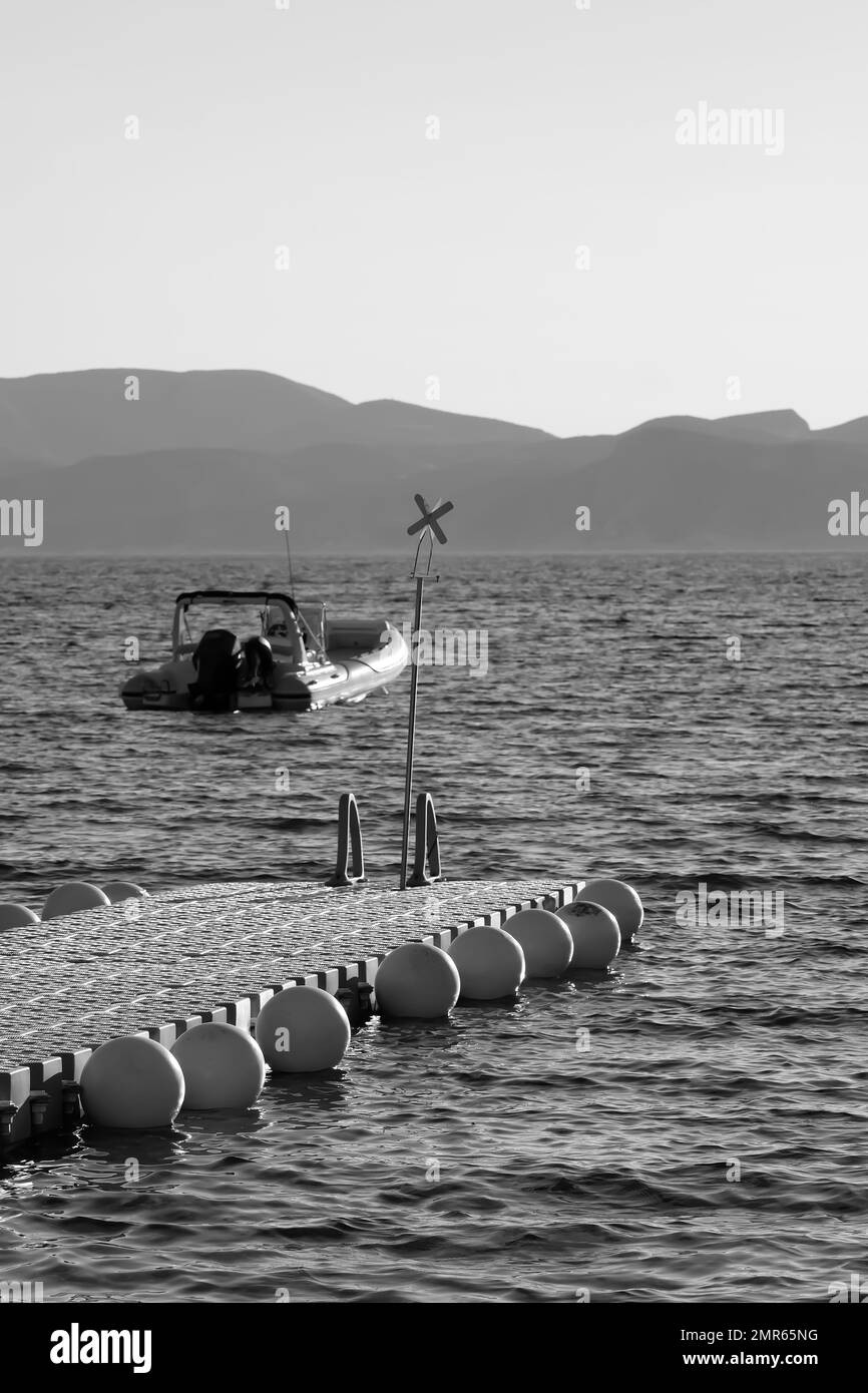 IOS, Grèce - 3 juin , 2021 : vue d'un quai flottant et d'un hors-bord à iOS Grèce en noir et blanc Banque D'Images