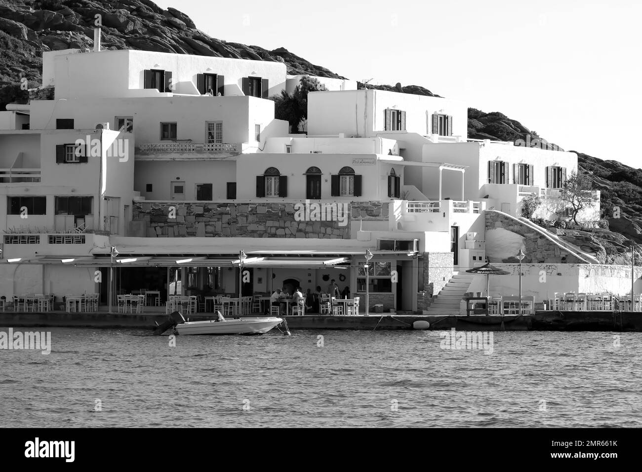 IOS, Grèce - 3 juin , 2021 : vue d'un hôtel blanchi à la chaux et d'une taverne de fruits de mer en face de la célèbre plage Mylopotas à iOS Grèce en noir et blanc Banque D'Images