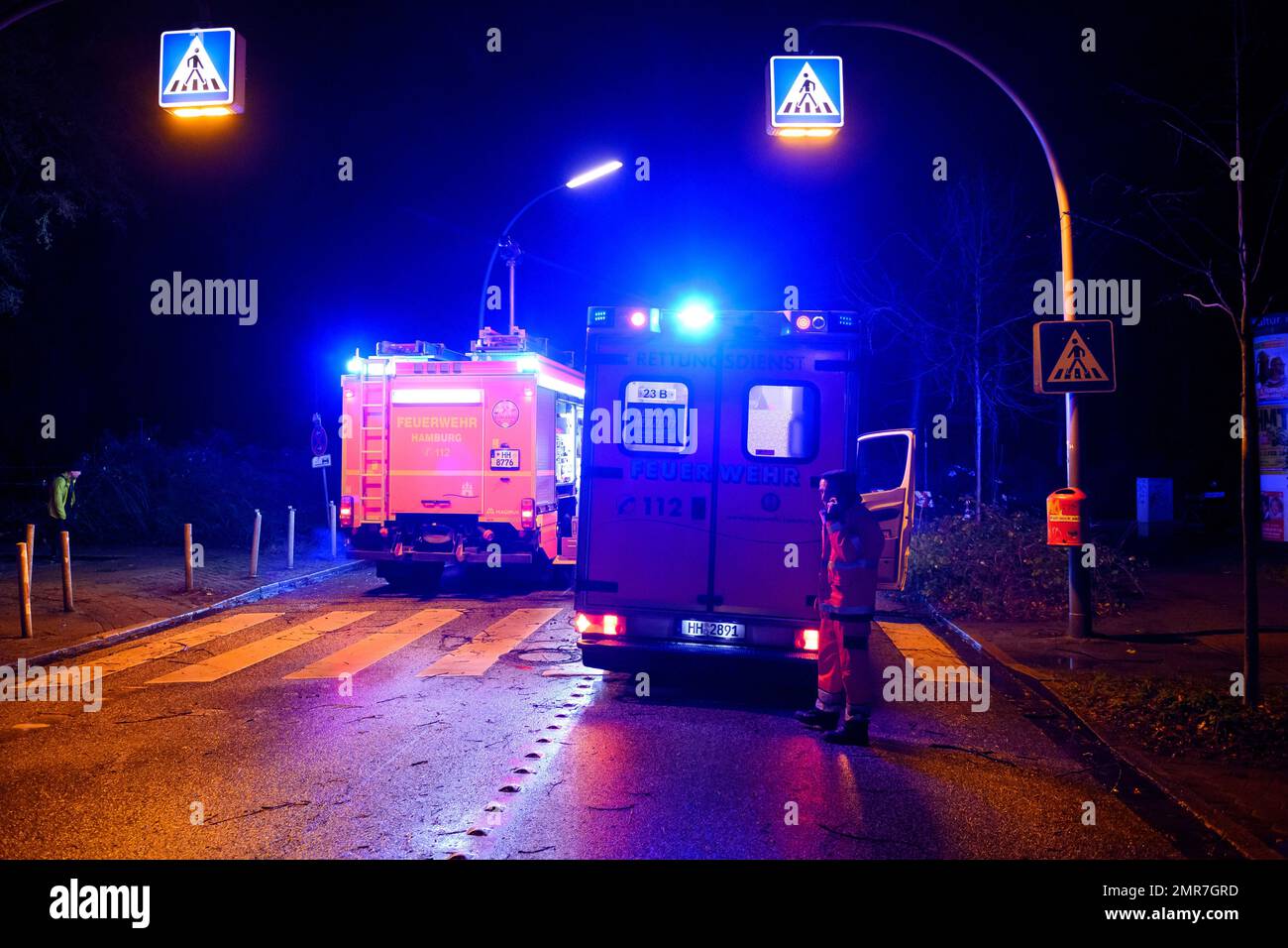 Hambourg, Allemagne. 31st janvier 2023. Une ambulance aux feux bleus se trouve à côté d'un camion d'incendie sur les lieux. Selon le service des incendies, un coup de foudre a fait tomber une partie d'un arbre sur plusieurs voitures à Hambourg-Winterhude mardi soir. Credit: Jonas Walzberg/dpa/Alay Live News Banque D'Images