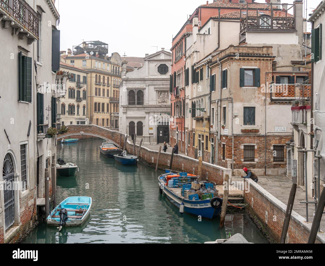 Scène du canal de Venise représentant un petit bateau dans un quartier résidentiel calme de Venise en hiver lors d'une journée brumeuse fraîche avec quelques personnes dans la rue Banque D'Images