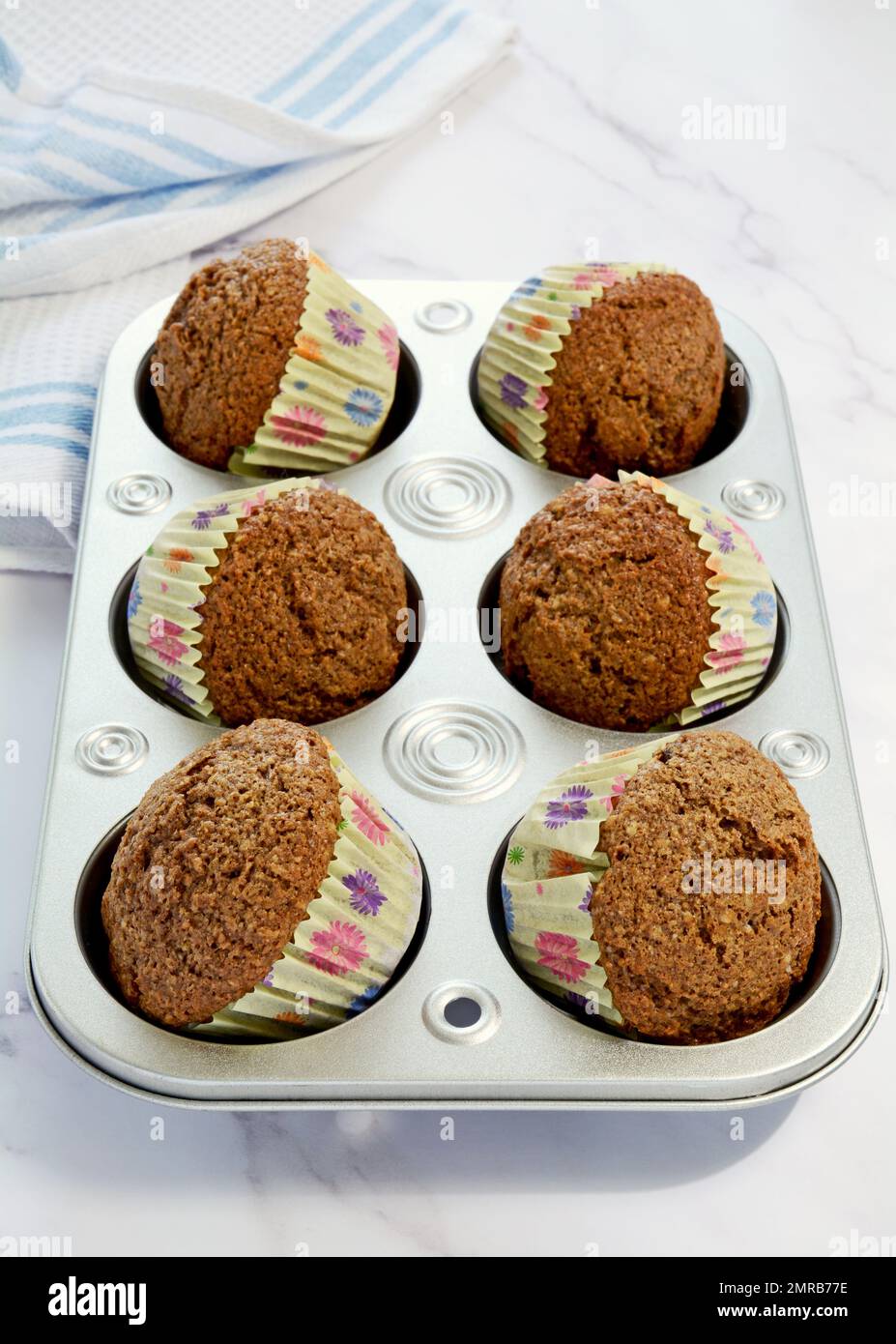 Muffins au son dans des petits gâteaux jaunes lumineux et ensoleillés sur fond de marbre. Pointe pour afficher les doublures au format vertical. Banque D'Images