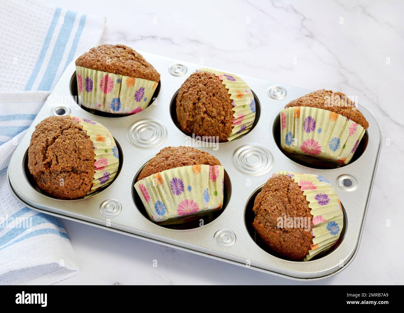 Muffins au son dans des petits gâteaux jaunes lumineux et ensoleillés sur fond de marbre. Pointe pour afficher les doublures au format horizontal. Banque D'Images