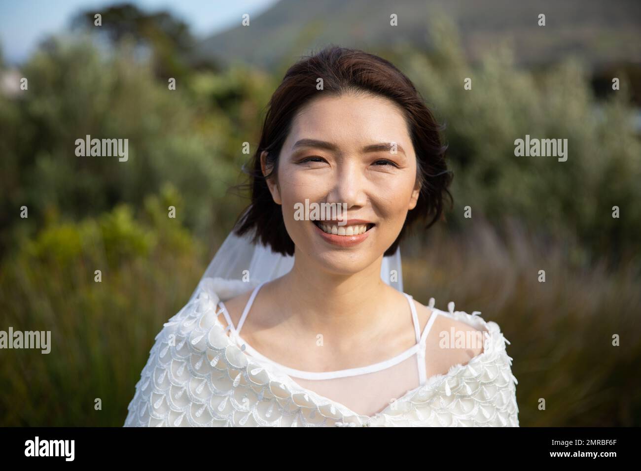 Portrait de la mariée asiatique heureuse en robe blanche souriant à l'extérieur de mariage, espace de copie Banque D'Images