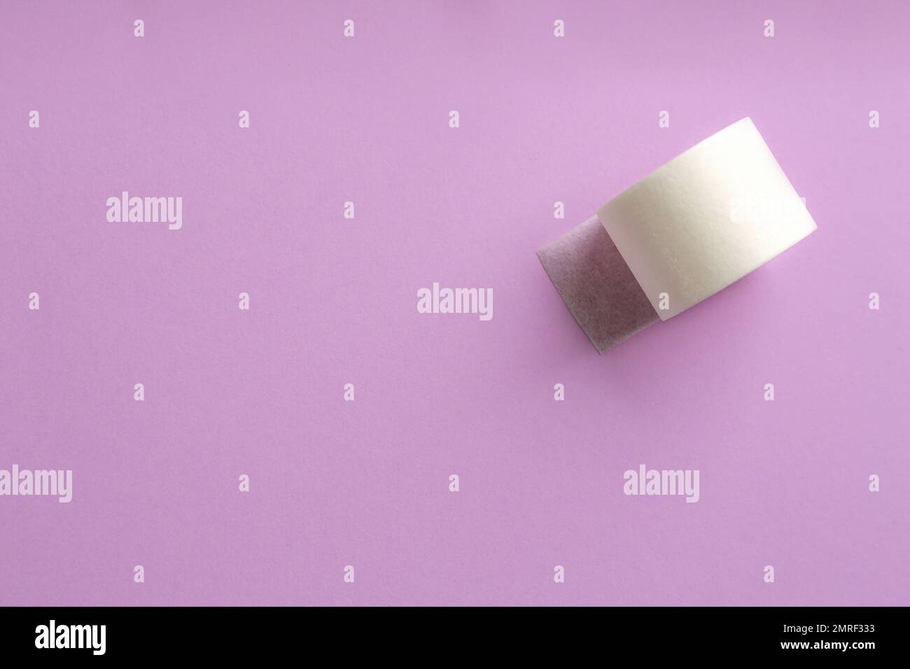 Rouleau de plâtre collé sur fond lilas, vue de dessus. Espace pour le texte Banque D'Images