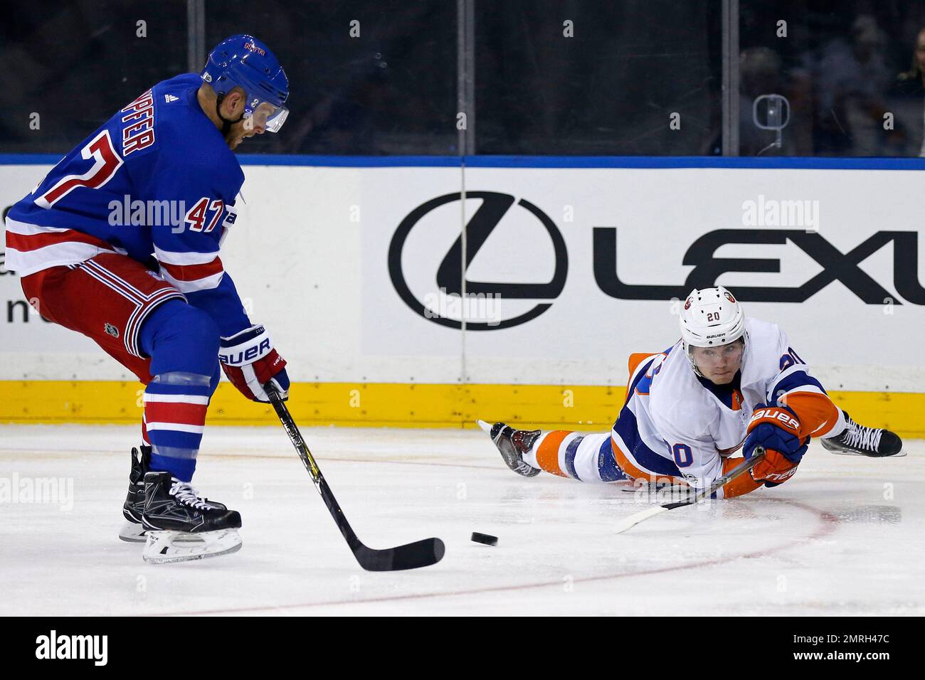 New York Islanders left wing Kieffer Bellows (20) attempts to pass the puck around New York Rangers defenseman Steven Kampfer (47) in the third period of a preseason NHL hockey game on Monday, Sept. 18, 2017, in New York. The Rangers won 1-0 in overtime. (AP Photo/Adam Hunger) Banque D'Images