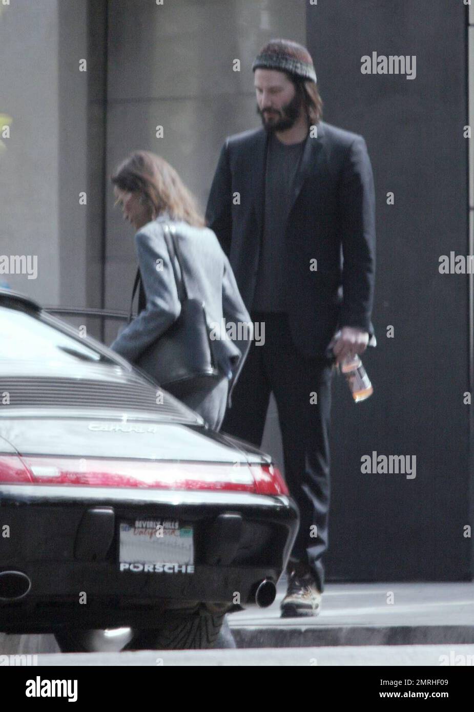 Exclusif !! Un regard triste Keanu Reeves ouvre la porte d'une voiture pour une femme compagnon après une visite de sa maison de Hollywood Hills à CA. L'acteur a montré à la femme en train de regarder les rénovations qu'il a fait à sa maison de style moderne depuis plusieurs mois. 3/4/07 Banque D'Images