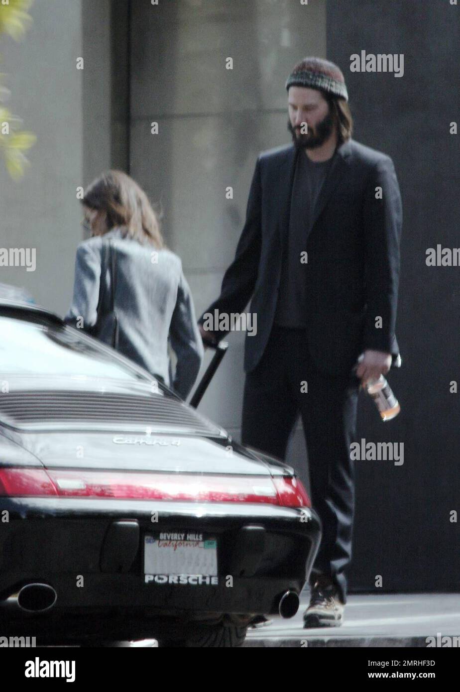 Exclusif !! Un regard triste Keanu Reeves ouvre la porte d'une voiture pour une femme compagnon après une visite de sa maison de Hollywood Hills à CA. L'acteur a montré à la femme en train de regarder les rénovations qu'il a fait à sa maison de style moderne depuis plusieurs mois. 3/4/07 Banque D'Images