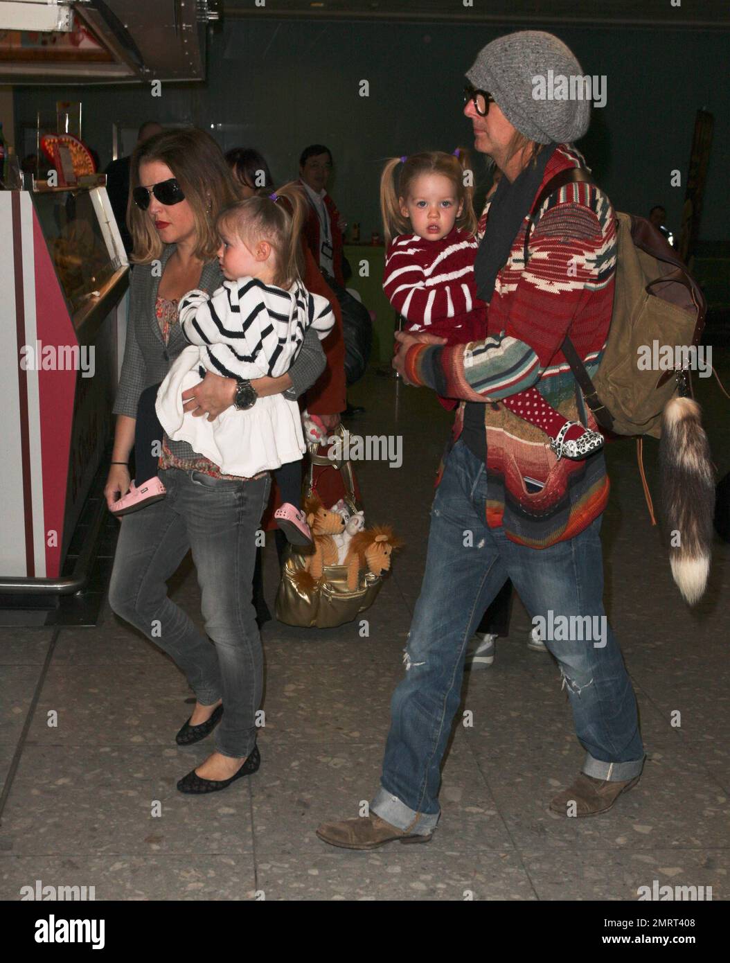 Lisa Marie Presley et son mari Michael Lockwood transportent leurs filles jumelles Harper Vivienne Ann et Finley Aaron Love par l'aéroport d'Heathrow après leur arrivée de LOS ANGELES. Lisa Marie, qui transportait un sac doré dont les animaux étaient farcis et portaient des lunettes de soleil avec des couvertures impaires sur les côtés, semblait décontractée dans une veste grise sur un haut à motifs floraux avec un pantalon et des chaussures plates gris. Londres, Royaume-Uni. 04/01/11. Banque D'Images