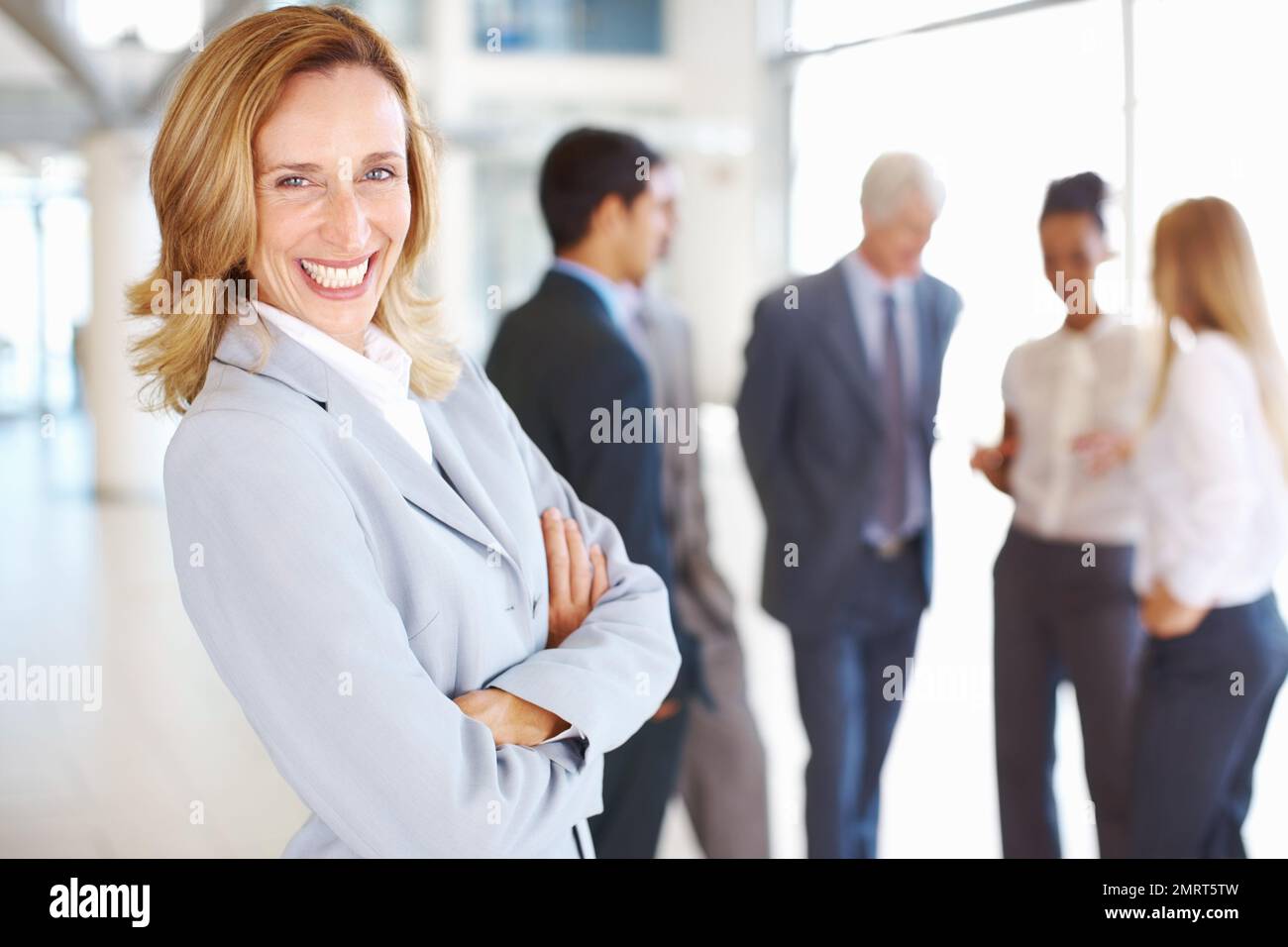 Une femme d'affaires heureuse avec des associés discutant. Portrait d'une femme d'affaires mûre heureuse avec des associés discutant en arrière-plan. Banque D'Images