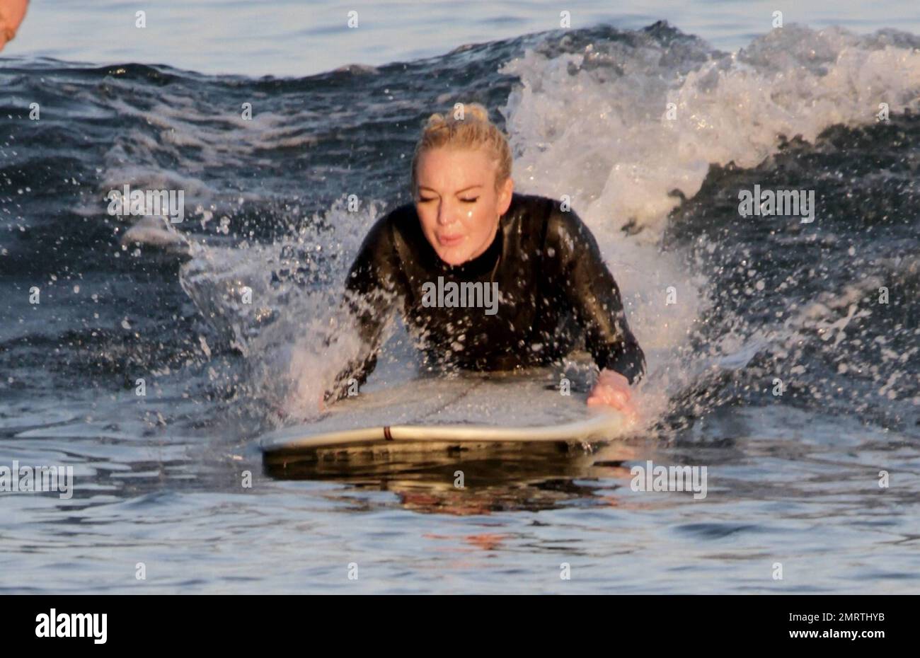 Lindsay Lohan tire quelques visages drôles tout en apprenant à surfer. Portant une combinaison noire, Lohan a tiré ses longs cheveux blonds dans un petit pain et a sauté dans les vagues avec une longue planche. Bien qu'il ait essuyé plusieurs fois, Lohan semblait passer un excellent moment. Malibu, Californie 16 août 2011. Banque D'Images