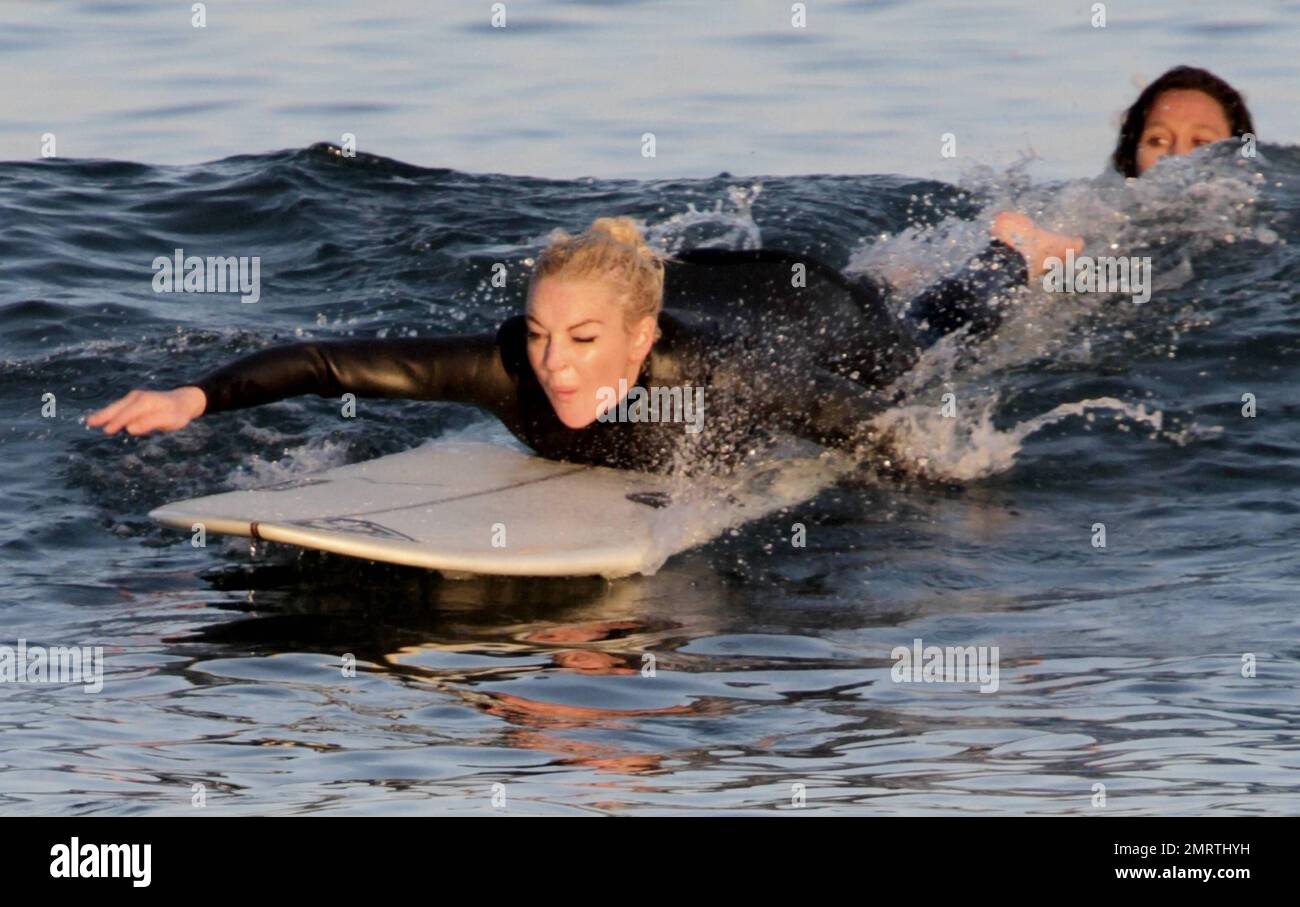 Lindsay Lohan tire quelques visages drôles tout en apprenant à surfer. Portant une combinaison noire, Lohan a tiré ses longs cheveux blonds dans un petit pain et a sauté dans les vagues avec une longue planche. Bien qu'il ait essuyé plusieurs fois, Lohan semblait passer un excellent moment. Malibu, Californie 16 août 2011. Banque D'Images