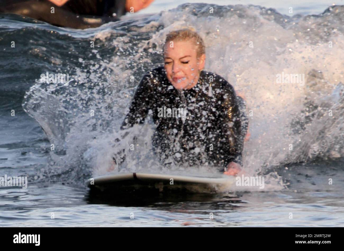 Lindsay Lohan tire quelques visages drôles tout en apprenant à surfer. Portant une combinaison noire, Lohan a tiré ses longs cheveux blonds dans un petit pain et a sauté dans les vagues avec une longue planche. Bien qu'il ait essuyé plusieurs fois, Lohan semblait passer un excellent moment. Malibu, Californie 16 août 2011. Banque D'Images