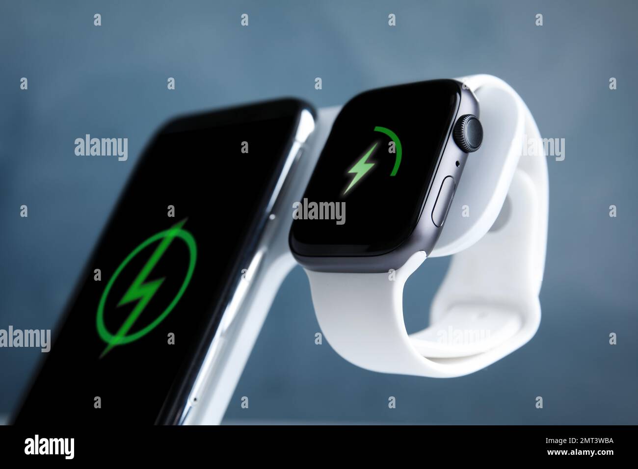 Recharge de la montre intelligente et du téléphone portable avec clavier sans fil sur fond bleu clair, gros plan Banque D'Images