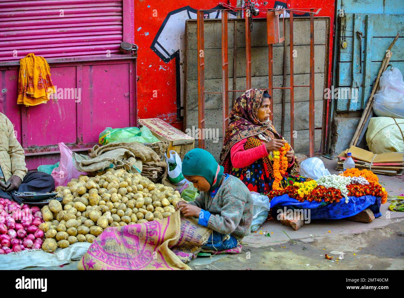 Varanasi, Uttar Pradesh, Inde, Un marchand de légumes vendant des pommes de terre et des fleurs dans la rue. Banque D'Images