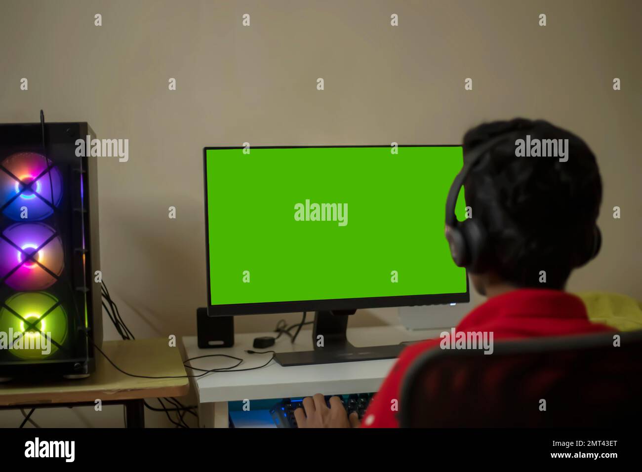 Un joueur jouant à un jeu vidéo en ligne sur son ordinateur personnel puissant avec écran vert - tourné de l'arrière Banque D'Images