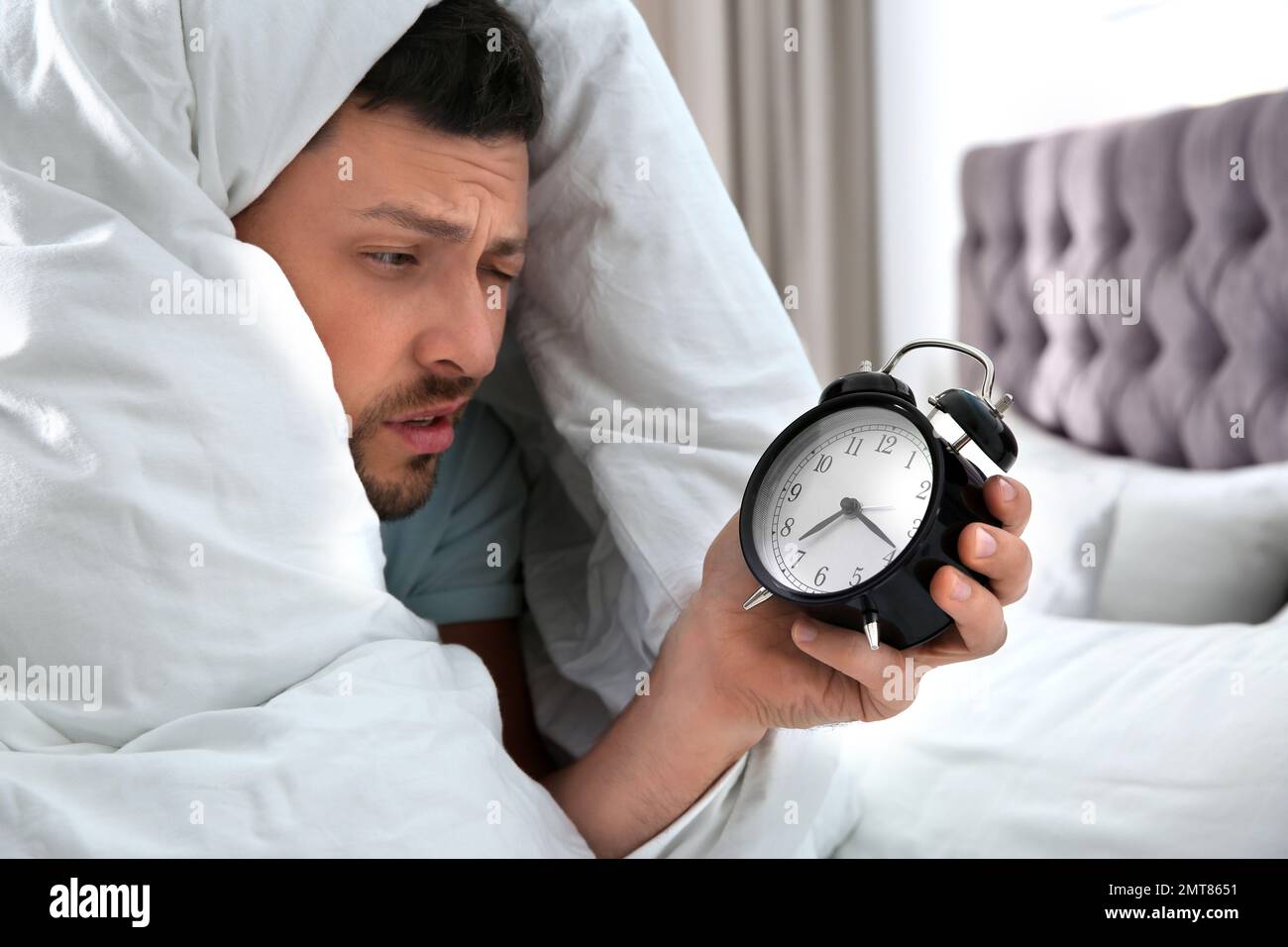 Homme endormi avec réveil à la maison le matin Photo Stock - Alamy