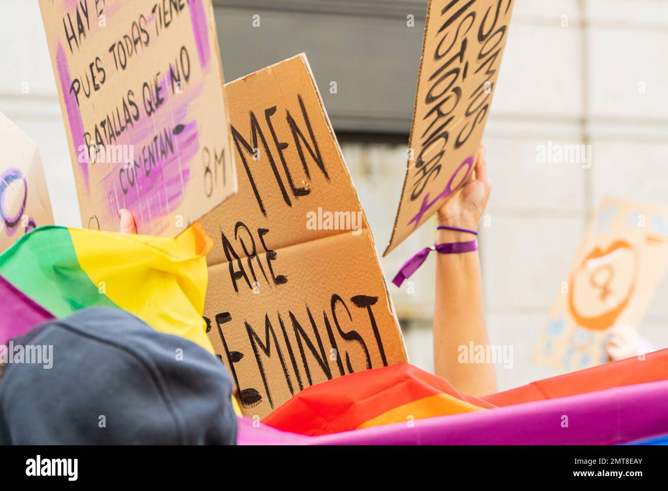 Jeune adulte gay avec drapeau lgbtq et soutien d'un message féministe écriteau sur une manifestation dans la rue Banque D'Images