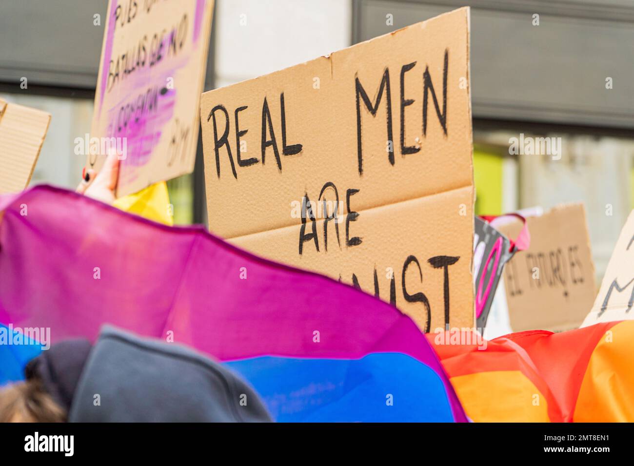 Jeune adulte gay avec drapeau lgbtq et soutien d'un message féministe écriteau sur une manifestation dans la rue Banque D'Images