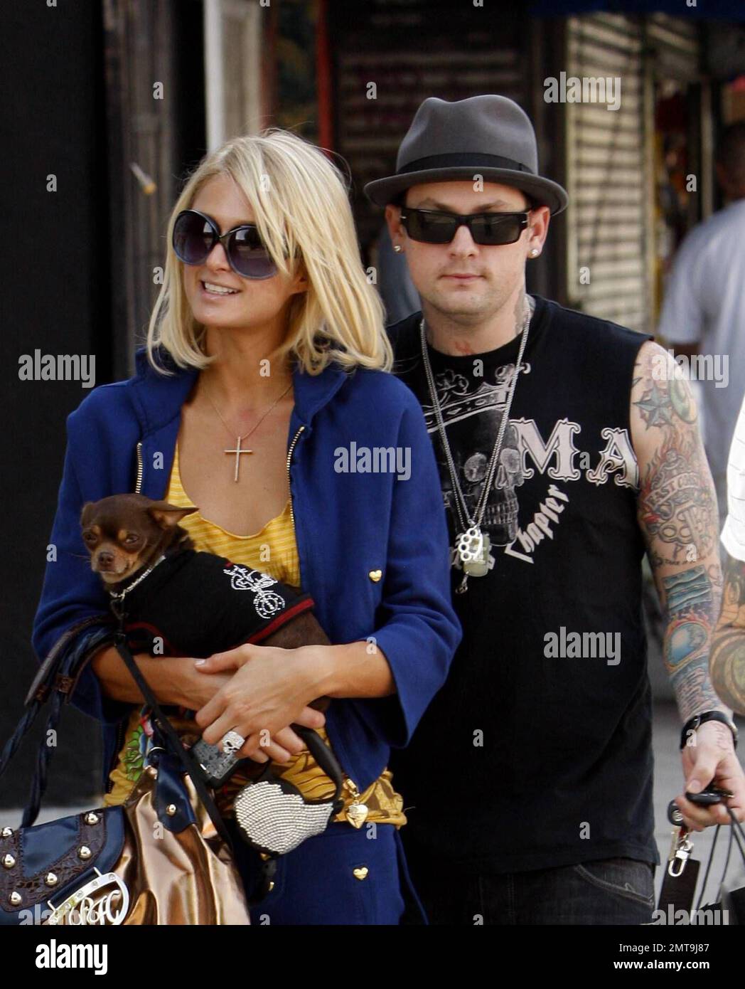 Une de ces choses n'est pas comme les autres! Paris Hilton, avec son petit chien en panne, semble un peu hors de place avec sa tenue colorée et son gros chapeau bleu alors qu'elle et son petit ami Benji Madden font un arrêt pour faire du shopping au magasin Benji, DCMA collective. Hollywood, Californie. 5/20/08. Banque D'Images