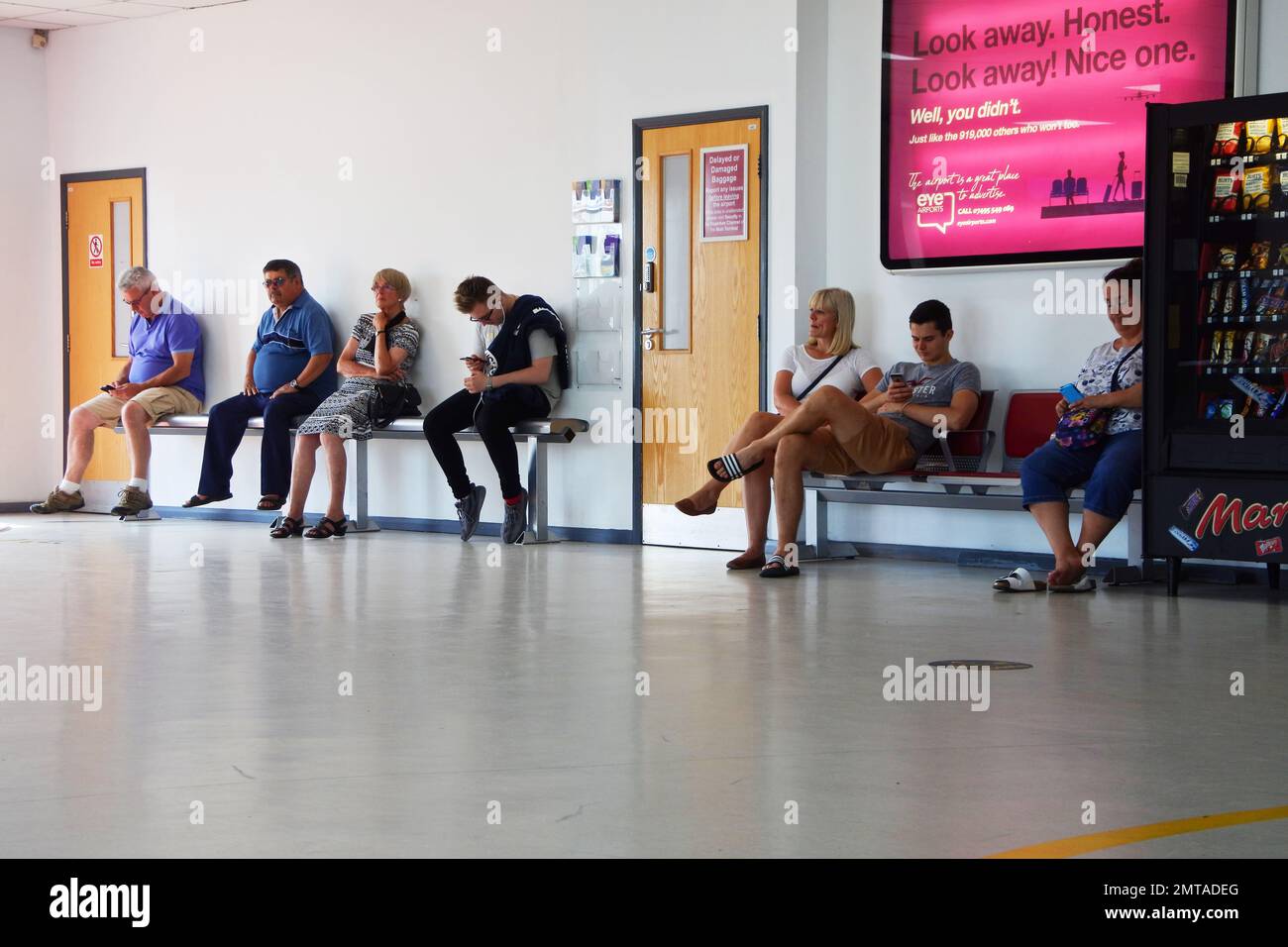 Les personnes qui attendent dans le hall des arrivées de l'aéroport d'Exeter - John Gollop Banque D'Images