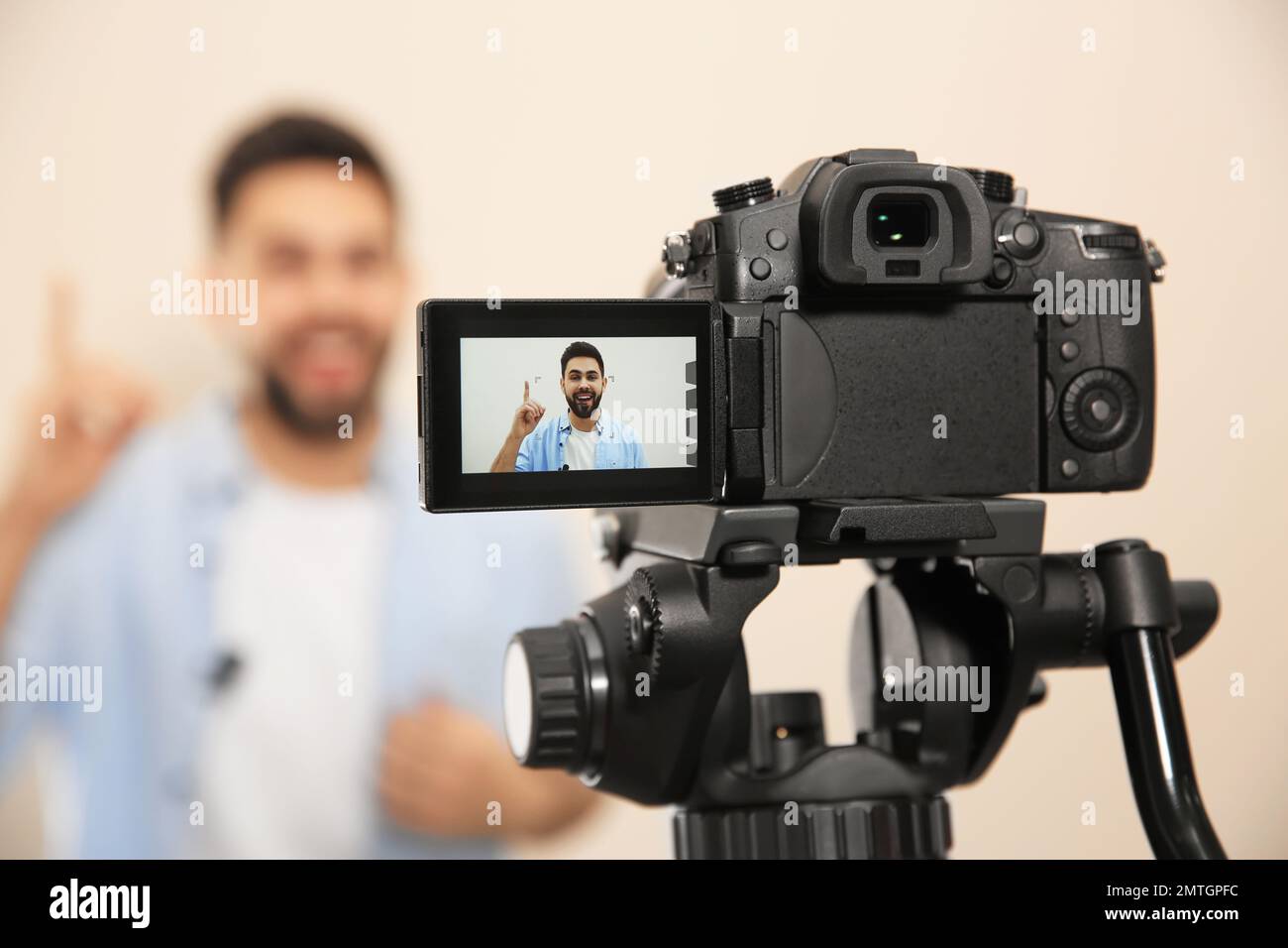 Jeune blogueur de tournage vidéo avec caméra sur fond beige, mise au point sur l'écran Banque D'Images
