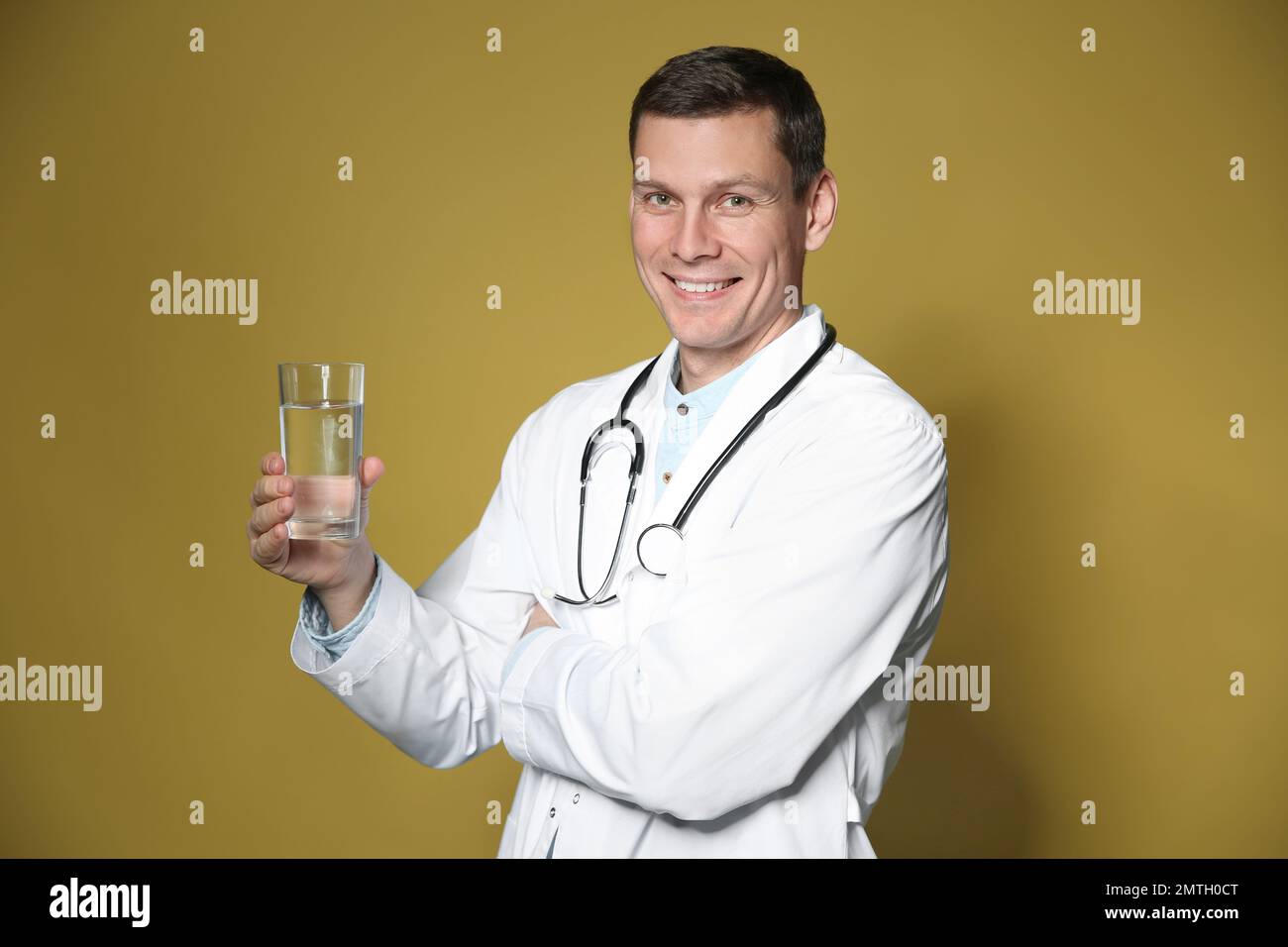 Nutritionniste tenant un verre d'eau pure sur fond jaune Banque D'Images