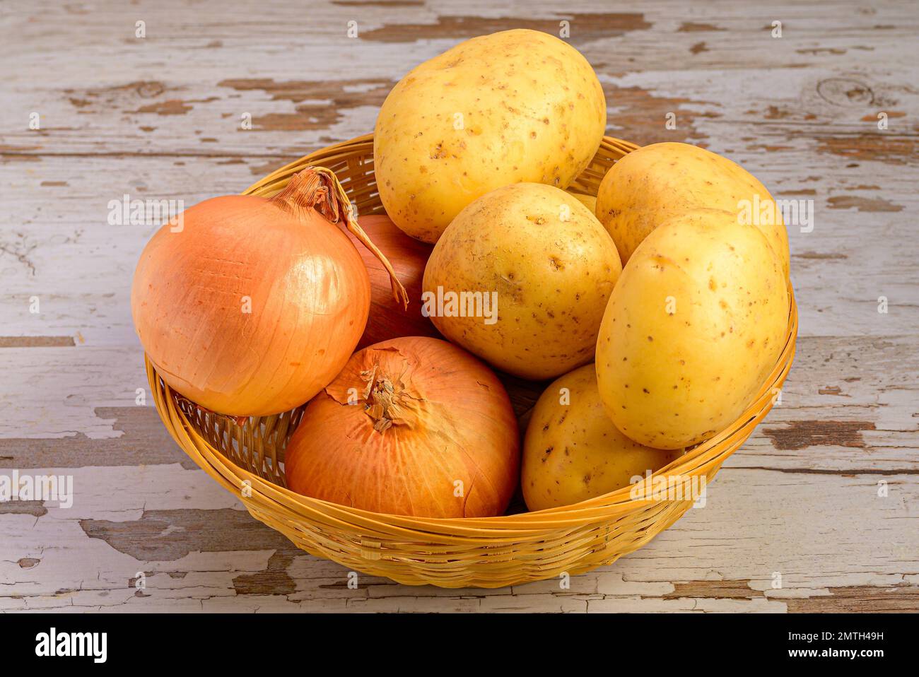 Un gros plan de pommes de terre et d'oignons dans un panier en osier sur  une surface en bois Photo Stock - Alamy
