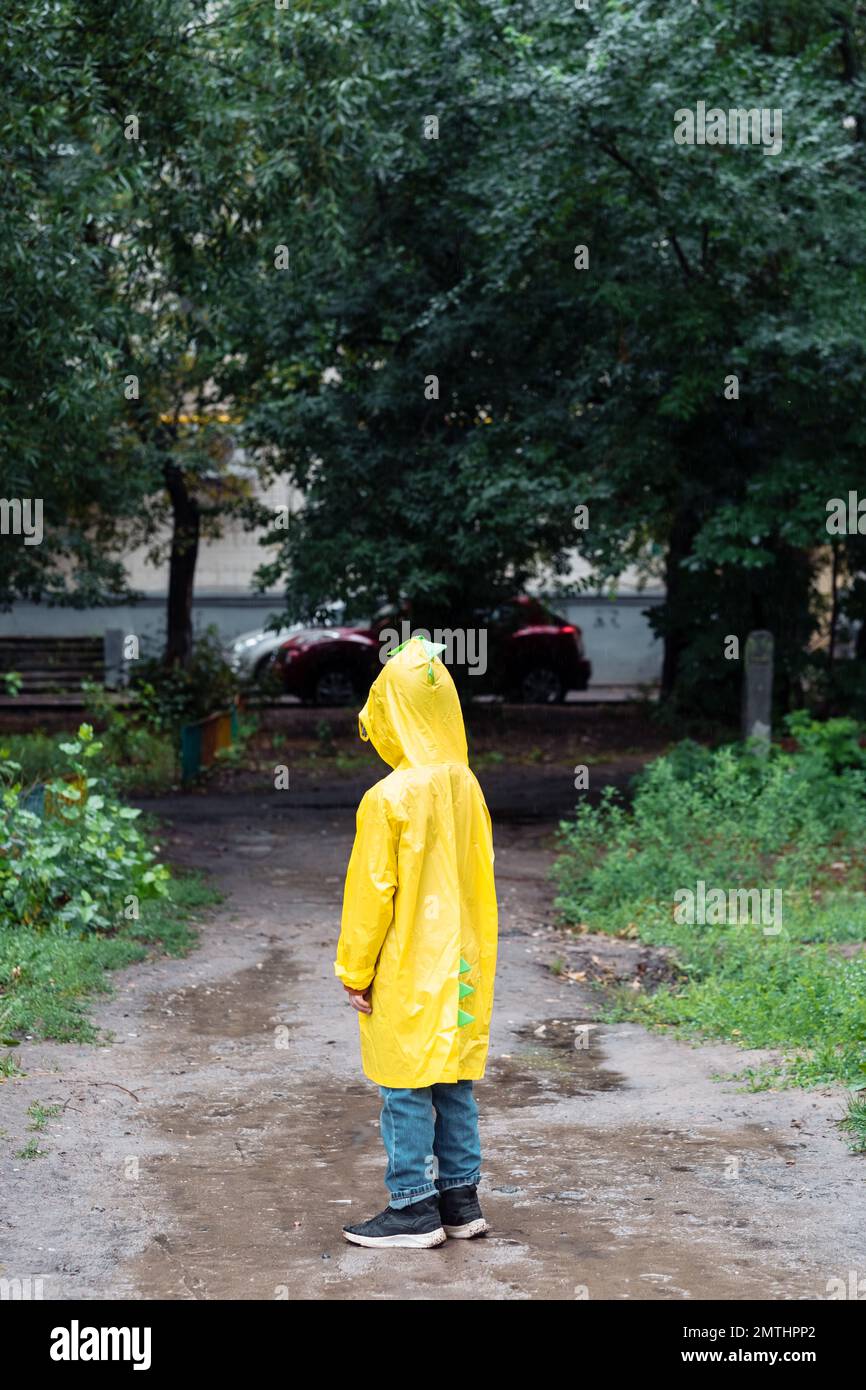 un garçon solitaire dans un imperméable jaune s'est perdu dans le parc Banque D'Images