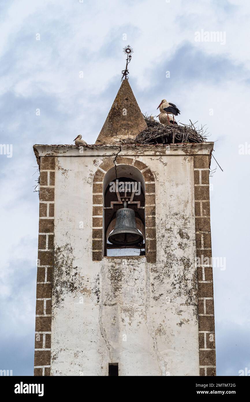 Nid de cigognes au sommet de l'ancien clocher en pierre avec croix de fer à Herreruela, Estrémadure en Espagne. Le paradis des randonneurs. Banque D'Images