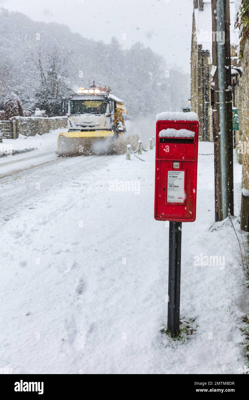 Une voiture de gritter et une boîte téléphonique rouge dans la neige profonde à Hutton le Hole, dans les North Yorkshire Moors, au Royaume-Uni Banque D'Images