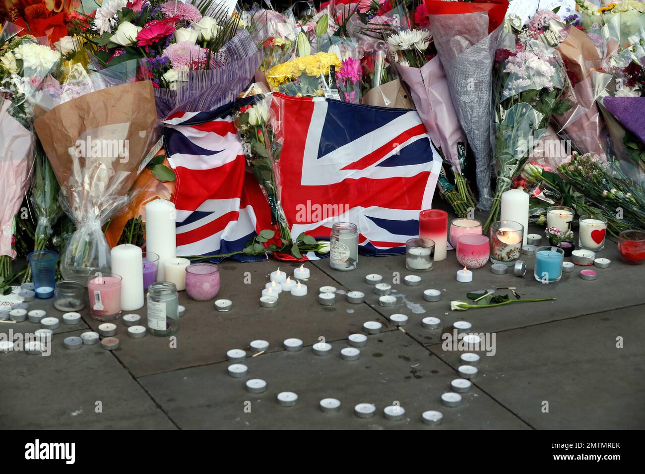 Flowers and candles are seen after a vigil in Albert Square, Manchester, England, Tuesday May 23, 2017, the day after the suicide attack at an Ariana Grande concert that left 22 people dead as it ended on Monday night. (AP Photo/Kirsty Wigglesworth) Banque D'Images