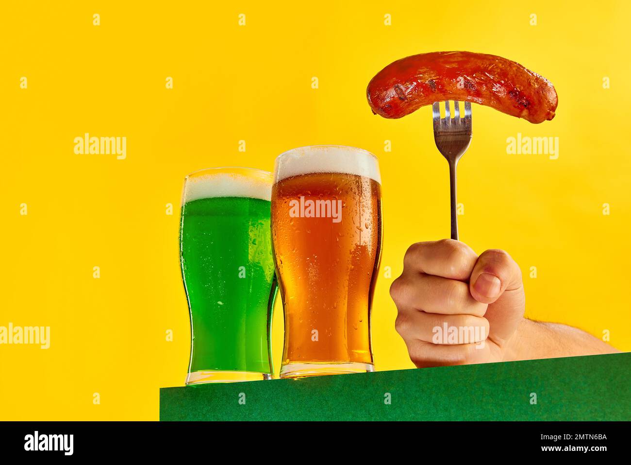 Deux verres de bière fraîche et de bière mousseuse lager et saucisse grillée à la fourchette sur fond jaune. Concept de la fête de St patrick, brasserie Banque D'Images