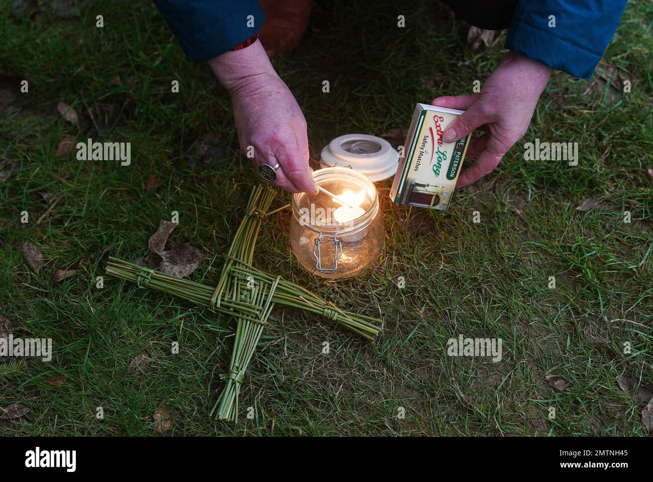 Nora Creed allume une bougie le long d'une rue traditionnelle Croix de Brigid's faite de rushes avant de mener une cérémonie pour embrasser le devine féminin et honorer le saint, au puits Saint de St Brigid's à Co Kildare. 1 février marque le jour de St Brigid's qui est vu par beaucoup en Irlande comme le premier jour du printemps. Date de la photo: Mercredi 1 février 2023. Banque D'Images