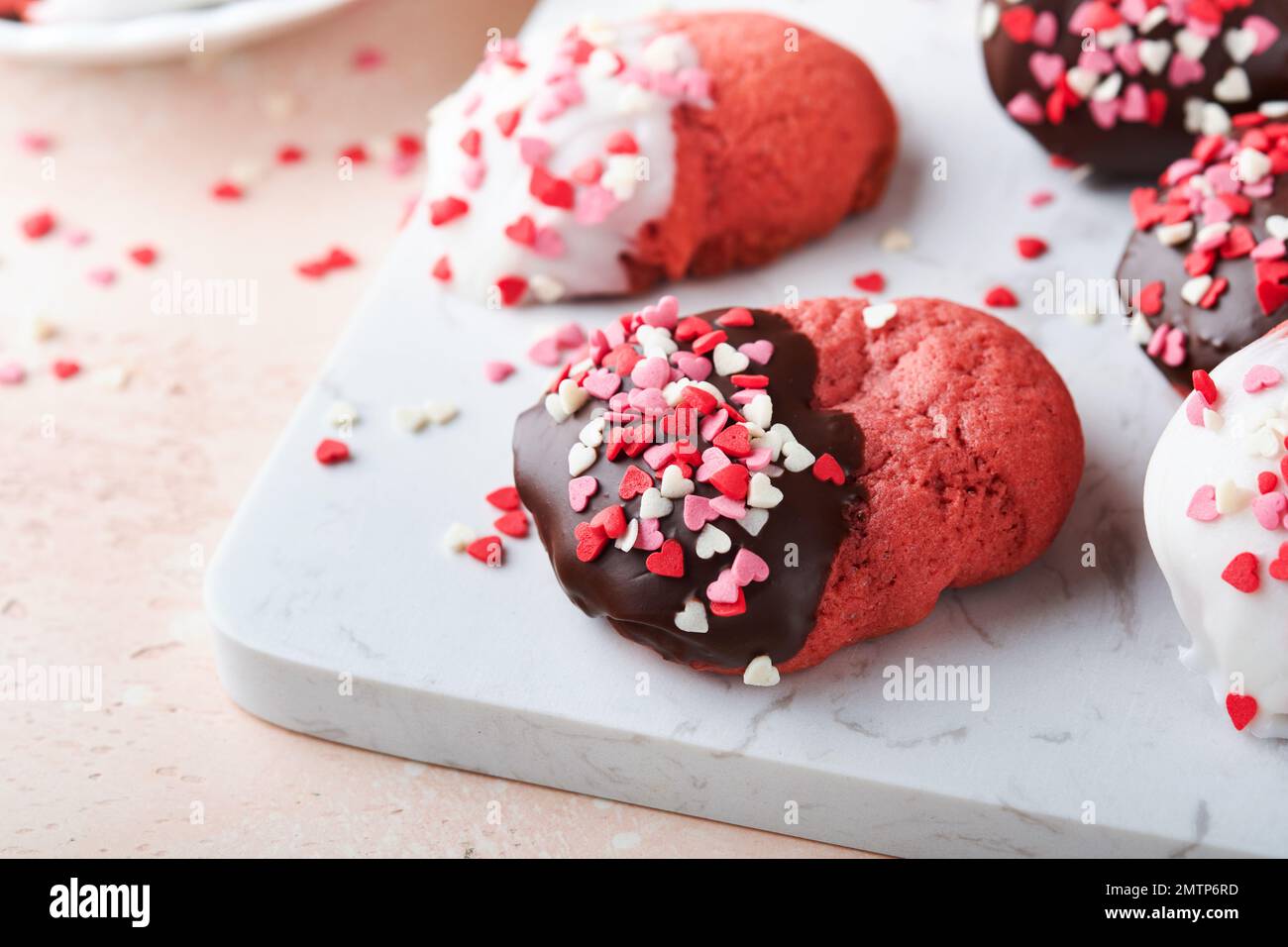 Petits gâteaux de Saint-Valentin. Biscuits sablés au chocolat noir et blanc glacis et coeur sur plaque sur fond blanc. Fête des mères. Femmes d Banque D'Images