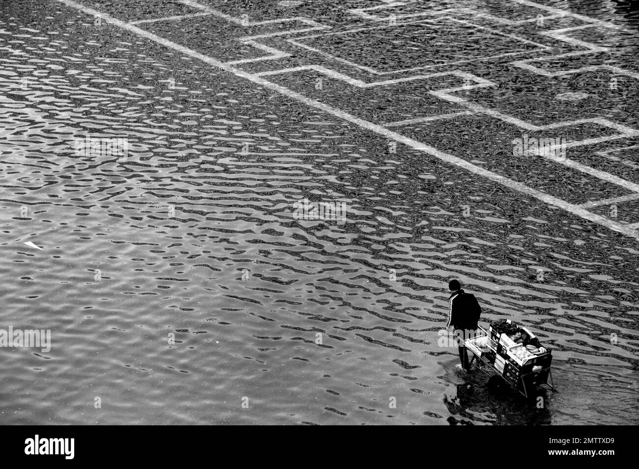 Un travailleur de l'autre côté de la place Saint-Marc sur la Venise inondée lors d'une alerte acqua-alta (haute eau) à Venise, Italie, lundi 02 2015. Banque D'Images